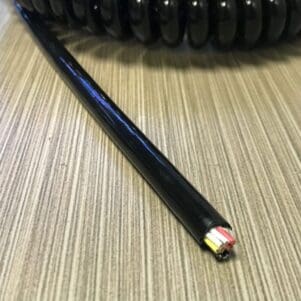 A EC2210 - Electronic Coiled Cord 22 Gauge with 10 Conductors - No Shield on a table.