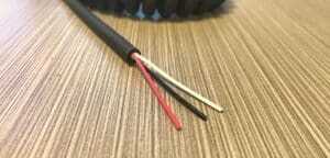 A black and red wire on top of a wooden table.