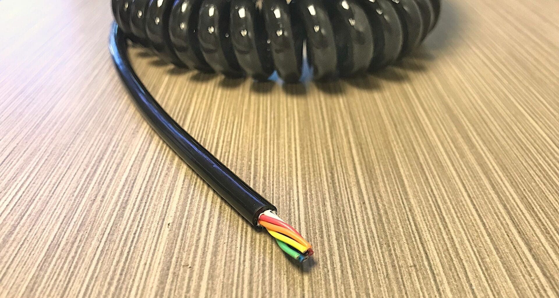 A black coiled cable on top of a table.