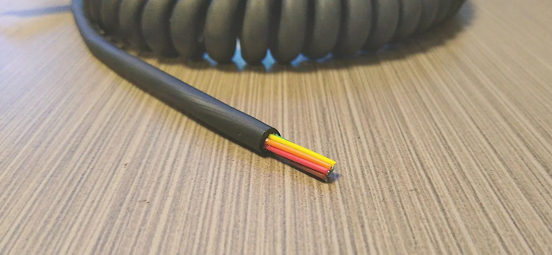 A black and yellow EC266 - Electronic Coiled Cord 26 Gauge with 6 Conductors - No Shield on a table.