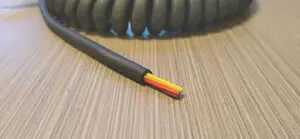 A black and yellow EC268 - Electronic Coiled Cord 26 Gauge with 8 Conductors - No Shield cable on a table.