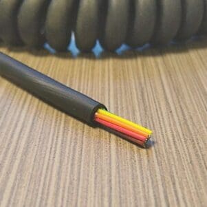 A black and yellow EC268 - Electronic Coiled Cord 26 Gauge with 8 Conductors - No Shield cable on a table.