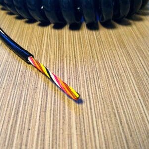 A EC287 - Electronic Coiled Cord 28 Gauge with 7 Conductors - Non-Shielded is sitting on a table.