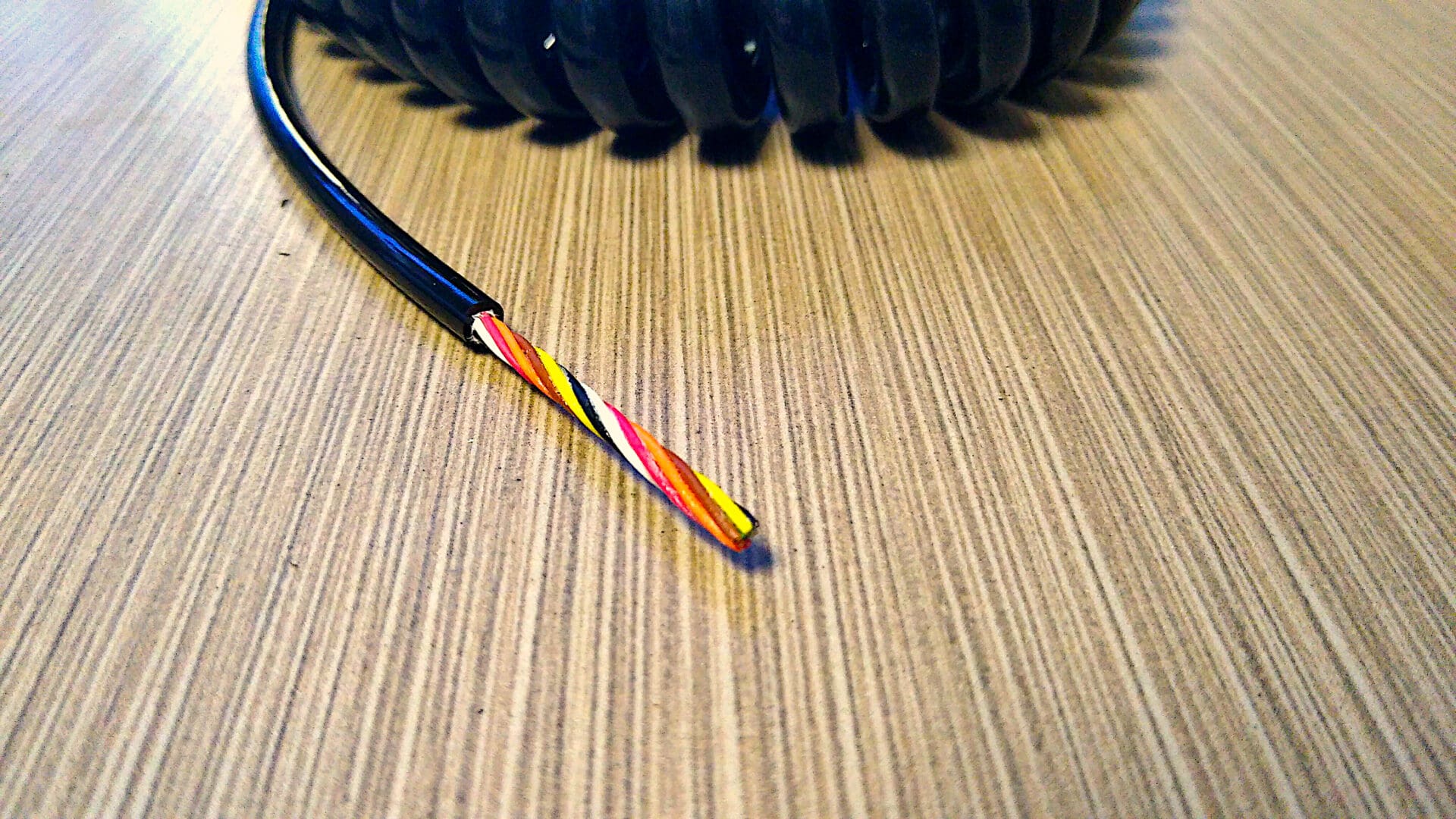 A EC287 - Electronic Coiled Cord 28 Gauge with 7 Conductors - Non-Shielded is sitting on a table.