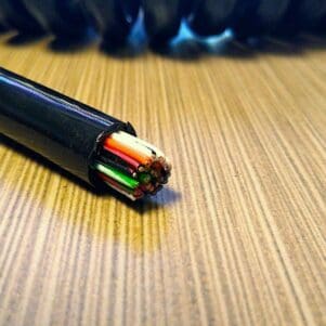 A ECS2227 - Electronic Coiled Cord 22 Gauge with 27 Conductors - Aluminum Shielded with colored wires on top of a table.