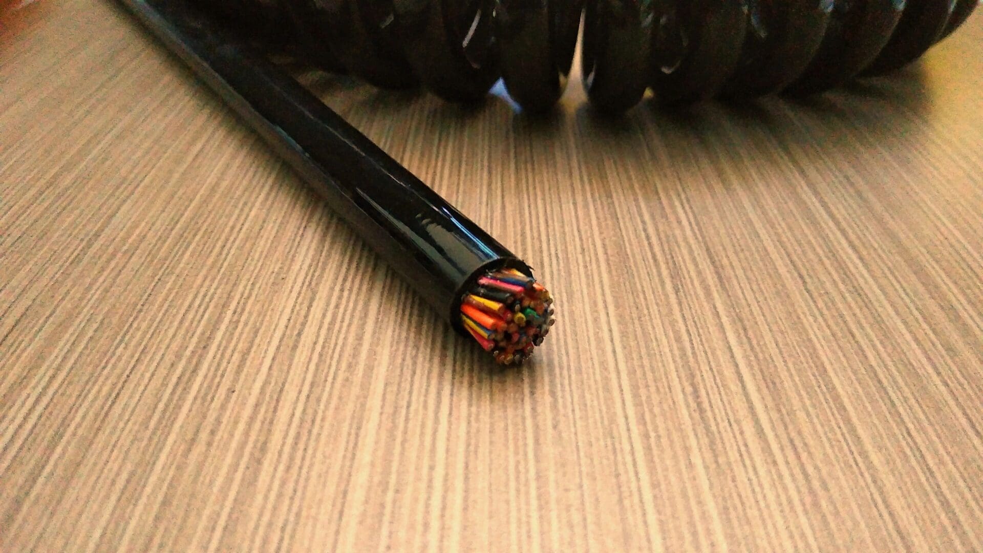 A black wire is sitting on top of a wooden table.