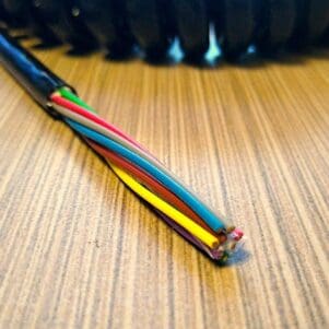 ECS228 - Electronic Coiled Cord 22 Gauge with 8 Conductors - Aluminum Shielded sitting on top of a wooden table.