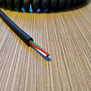 A MCC244 - Electronic Coiled Cord 24 Gauge with 4 Conductors 2 - Shielded - Audio Communication / Microphone Coil Cable on a table.