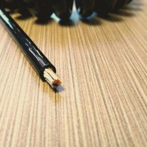 A black ECS2812 - Electronic Coiled Cord 28 Gauge with 12 Conductors - Aluminum Shielded on a wooden table.