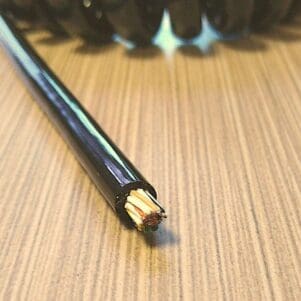 A ECS2815 - Electronic Coiled Cord 28 Gauge with 15 Conductors - Aluminum Shielded wire is sitting on top of a wooden table.