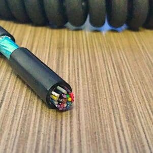 A ECS2822 - Electronic Coiled Cord 28 Gauge with 22 Conductors - Aluminum Shielded laying on top of a wooden table.