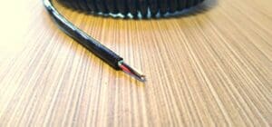 A black wire laying on top of a wooden table.