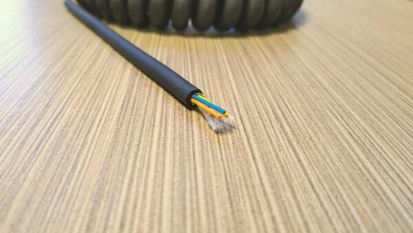 A black cable is sitting on top of a wooden table.