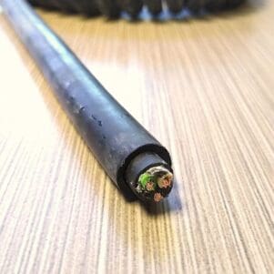 A PCE163 - Power Coiled Cord 16 Gauge with 3 Conductors - No Shield wire is sitting on a wooden table.