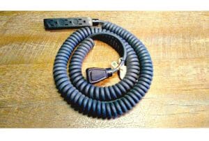 A Coiled Power Supply Cord with Molded Plugs on a wooden table.