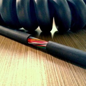 EC2425 - Electronic Coiled Cord 24 Gauge with 25 Conductors - No Shield located on top of a wooden table.