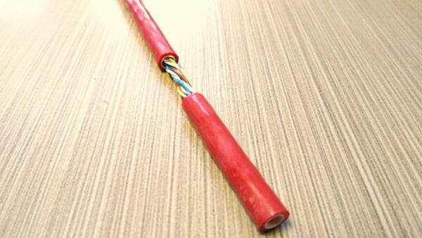 A red cable is sitting on top of a wooden table.