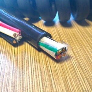 A PCE104 - Power Coiled Cord 10 Gauge with 4 Conductors - No Shield that are laying on top of a wooden table.