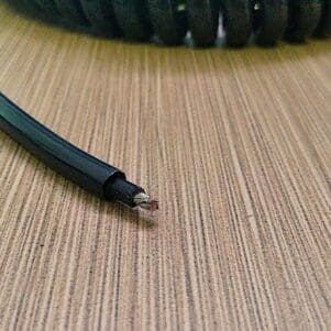 A black coiled cable on a wooden table.