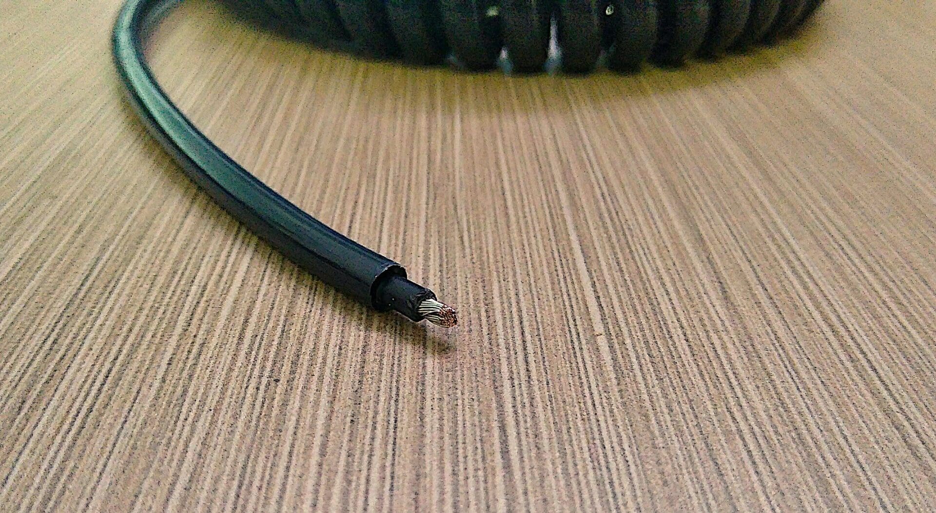 A black coiled cable on a wooden table.