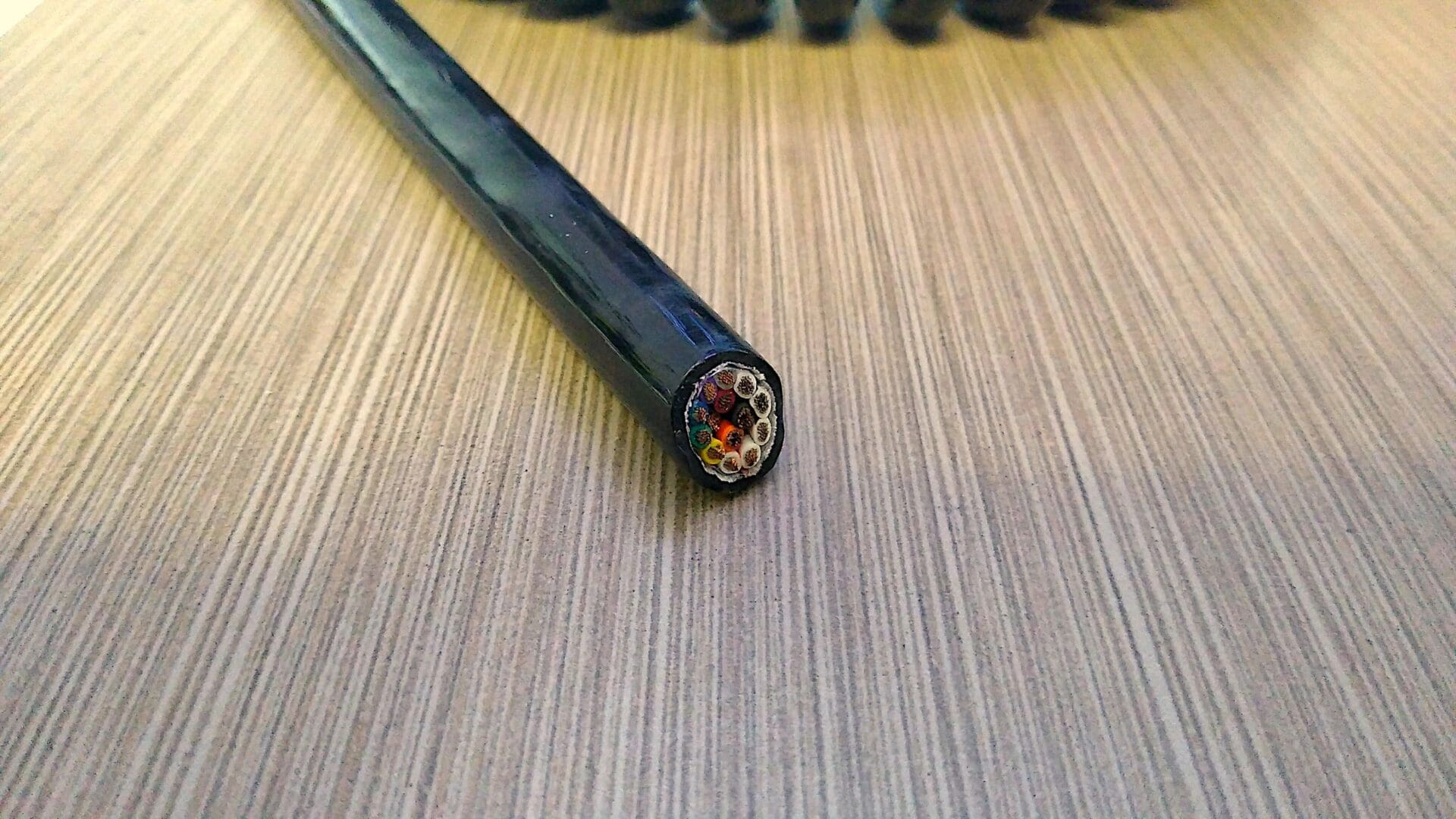 A black wire laying on top of a wooden table.