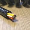 A black cable with colored wires laying on top of a table.