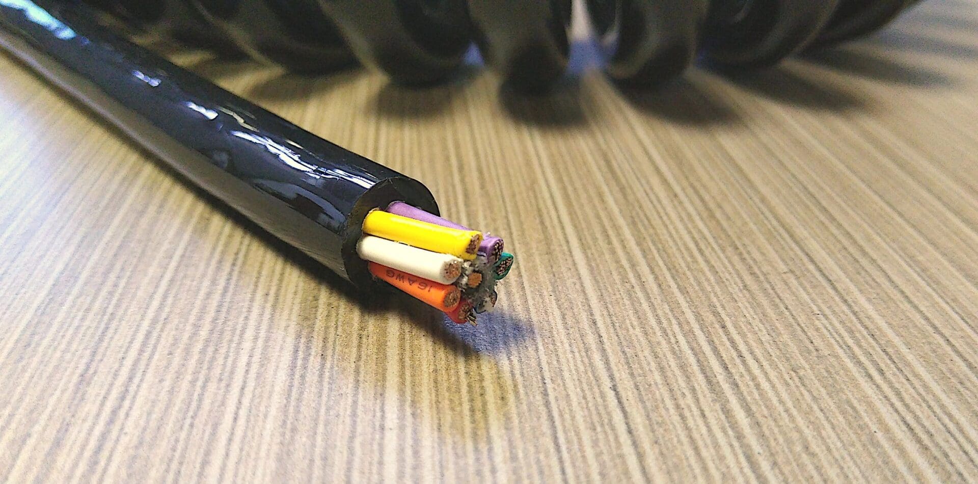 A black cable with colored wires laying on top of a table.