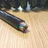 A black coiled cable on top of a wooden table.