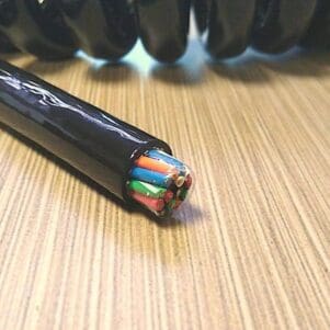 A black coiled cable on top of a wooden table.