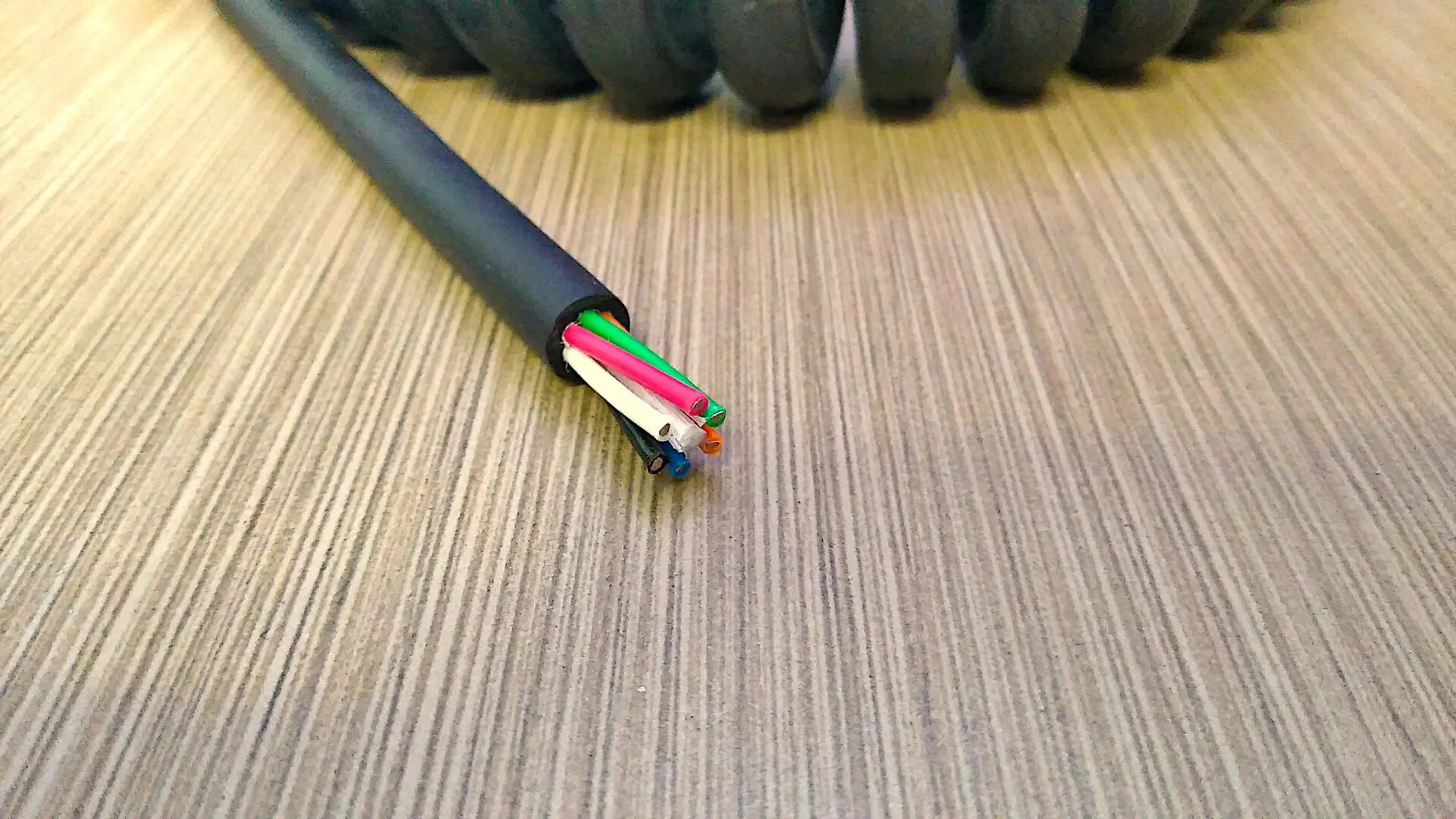A black and white cable laying on top of a wooden table.