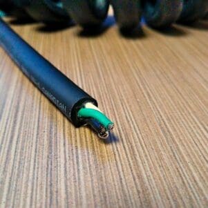 A PCJ163 - Power Coiled Cord 16 Gauge with 3 Conductors - No Shield on a wooden table.