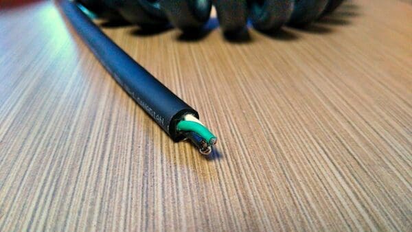 A PCJ163 - Power Coiled Cord 16 Gauge with 3 Conductors - No Shield on a wooden table.