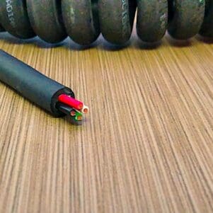 A PCJ164 - Power Coiled Cord 16 Gauge with 4 Conductors - No Shield laying on top of a wooden table.