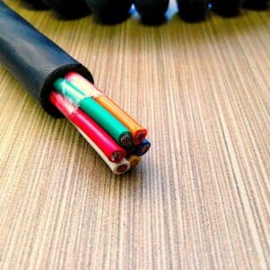 A PCO127 - Power Coiled Cord 12 Gauge with 7 Conductors - No Shield - 600 Volts cable with colored wires laying on top of a table.