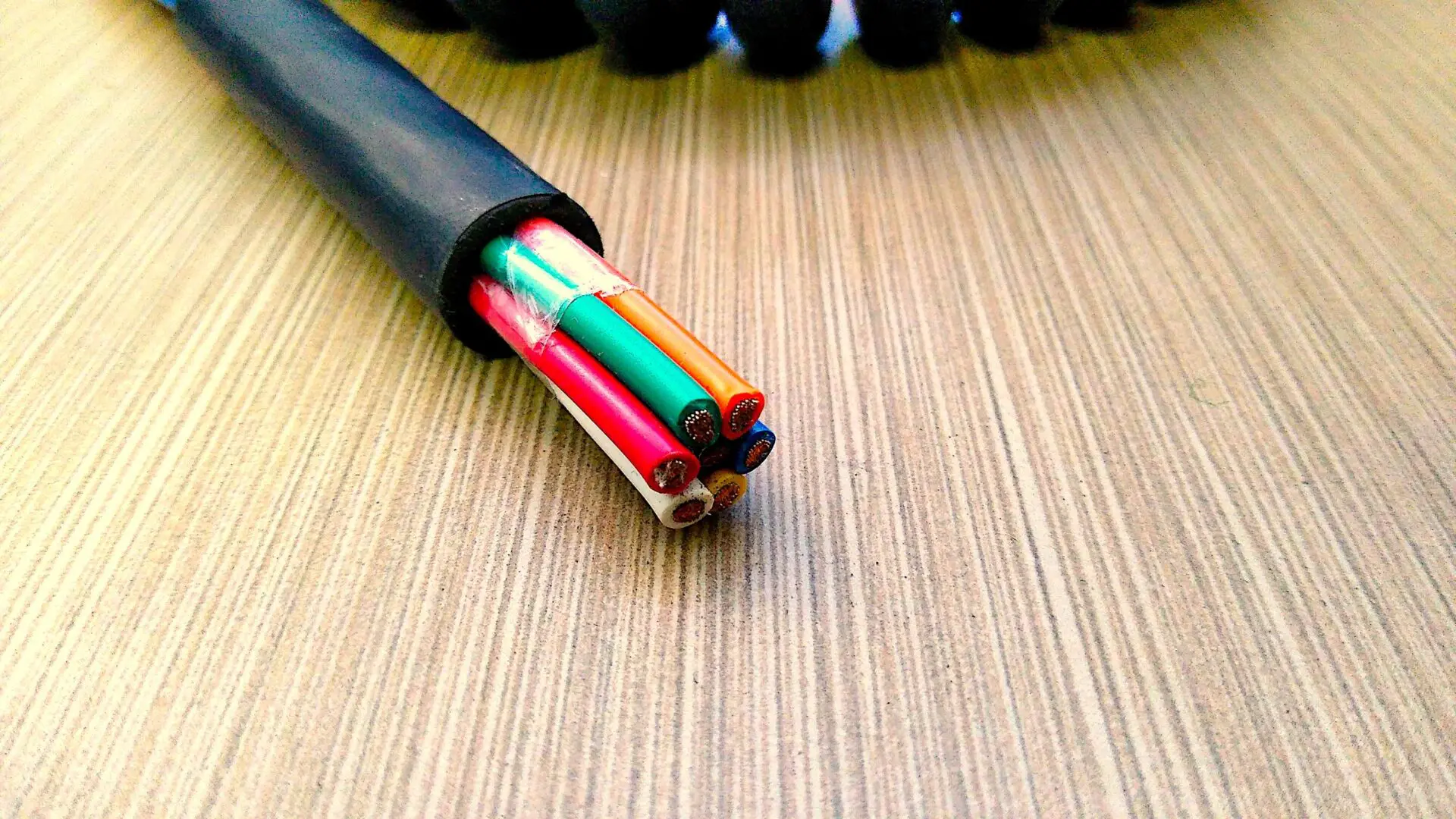 A PCO127 - Power Coiled Cord 12 Gauge with 7 Conductors - No Shield - 600 Volts cable with colored wires laying on top of a table.
