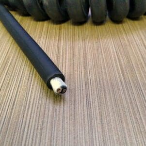 A PCO142 - Power Coiled Cord 14 Gauge with 2 Conductors - No Shield - 600 Volts on top of a wooden table.