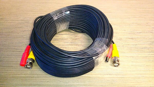 A coiled black Video Security Camera Wire with Connectors for CCTV Camera DVR Surveillance System on a textured grey surface.