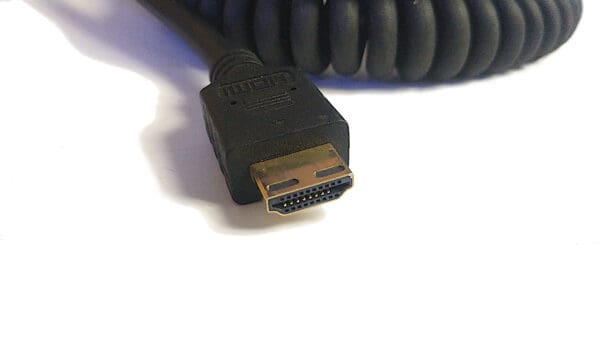 Close-up of an 8K Ultra High Speed HDMI cable connector on a white surface, highlighting its gold-plated pins and black casing.